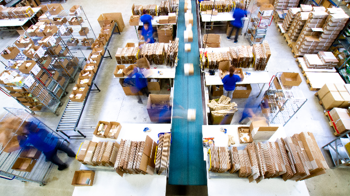 Fulfillment-Anbieter im Vergleich: Mitarbeiter der IDEAL GROUP beim Repackaging und Zusammenstellen von Bestellungen für den Versand